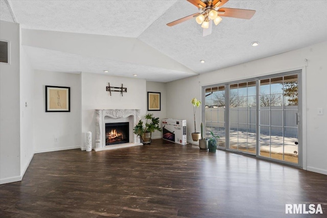 unfurnished living room with lofted ceiling, ceiling fan, a high end fireplace, a textured ceiling, and dark hardwood / wood-style flooring