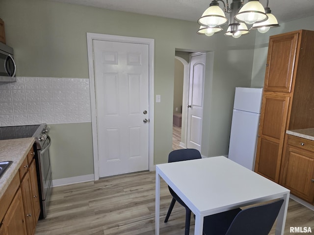 kitchen featuring pendant lighting, stainless steel appliances, light hardwood / wood-style floors, and a notable chandelier