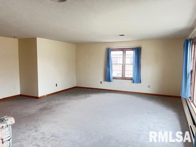 carpeted spare room featuring a textured ceiling and baseboard heating