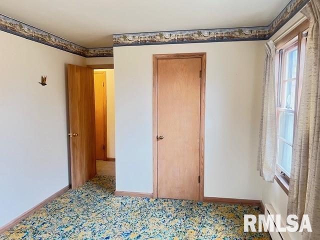 unfurnished bedroom featuring a baseboard heating unit