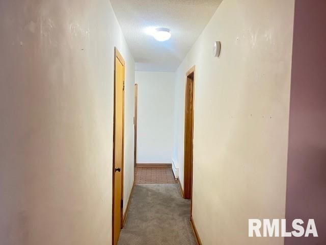 corridor featuring light colored carpet and a textured ceiling