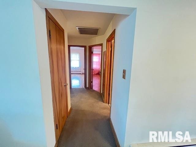 hall featuring dark carpet and baseboard heating