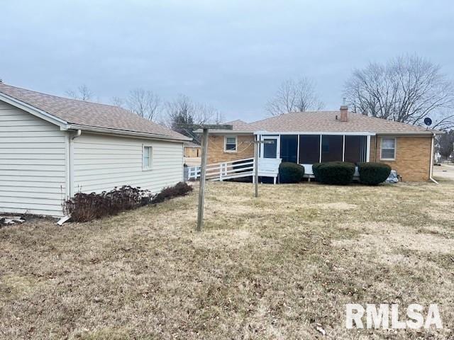 rear view of house featuring a yard and a sunroom