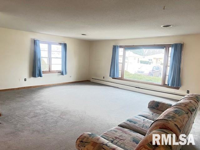 unfurnished living room featuring carpet flooring, a textured ceiling, and baseboard heating