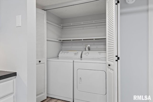 laundry area featuring light wood-type flooring, washing machine and clothes dryer, and a textured ceiling