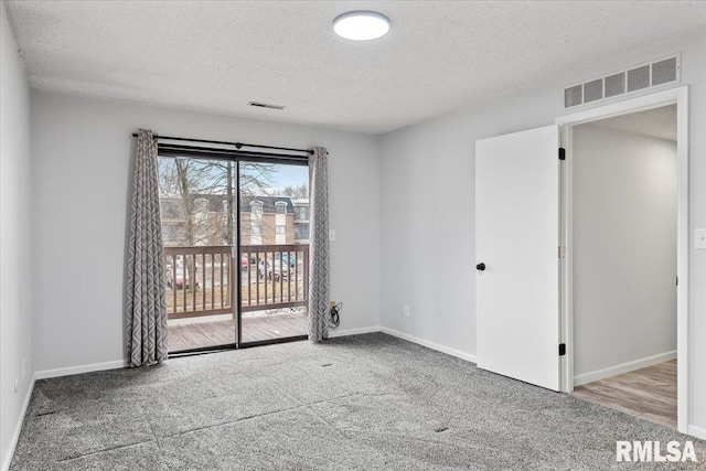 spare room featuring light colored carpet and a textured ceiling