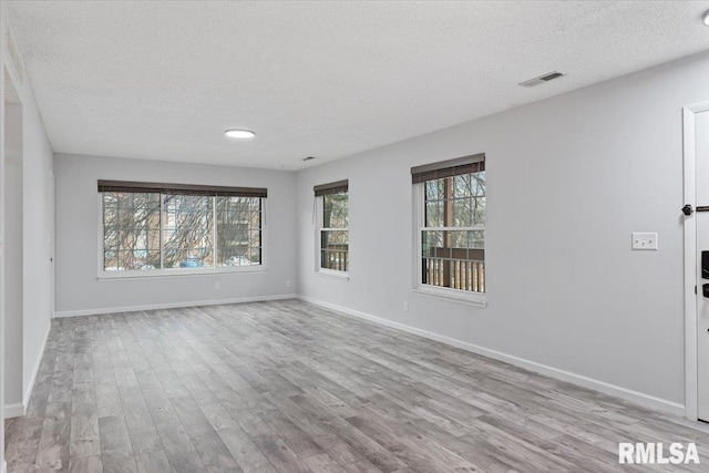 empty room with a textured ceiling and light wood-type flooring