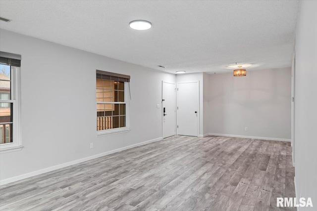 empty room with a textured ceiling and light wood-type flooring