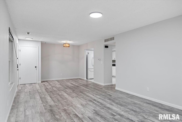 empty room featuring a textured ceiling and light hardwood / wood-style flooring