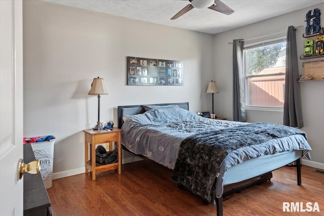 bedroom featuring ceiling fan, dark hardwood / wood-style floors, and a textured ceiling