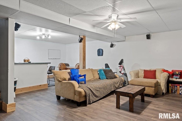 living room with hardwood / wood-style flooring, a paneled ceiling, and ceiling fan