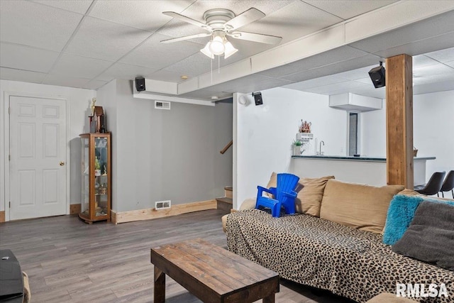 living room featuring hardwood / wood-style flooring, a paneled ceiling, and ceiling fan