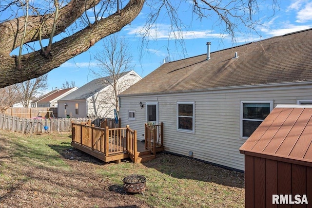 rear view of house with a wooden deck, a lawn, and an outdoor fire pit