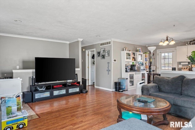 living room featuring crown molding, a chandelier, hardwood / wood-style floors, and a textured ceiling