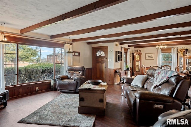 living room featuring a textured ceiling, a notable chandelier, beam ceiling, and wood walls