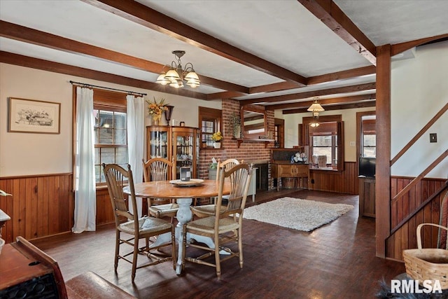 dining space featuring wood-type flooring, a healthy amount of sunlight, a chandelier, and beam ceiling