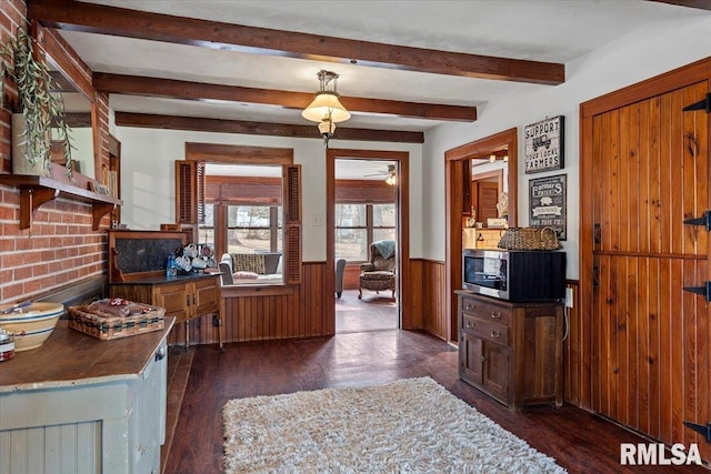 interior space with beamed ceiling, wooden walls, and dark wood-type flooring