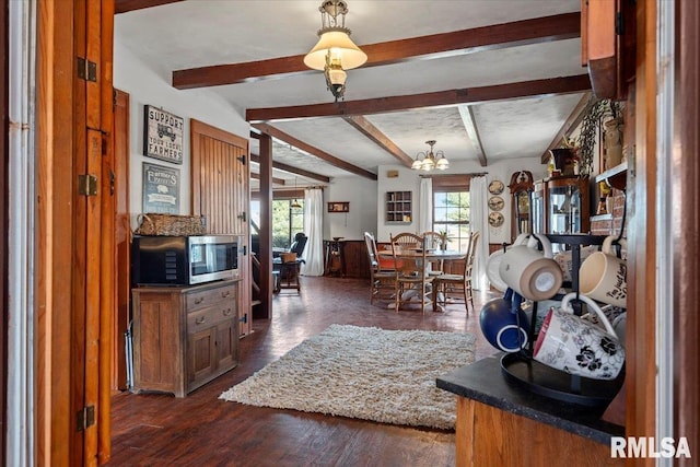 interior space with dark wood-type flooring, beam ceiling, and a notable chandelier