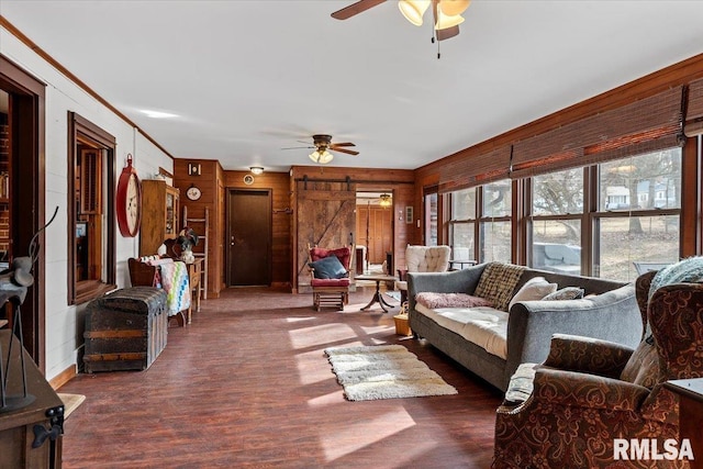 living room featuring dark hardwood / wood-style floors, ceiling fan, ornamental molding, and a barn door