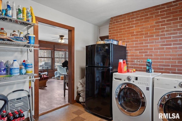 clothes washing area featuring brick wall, washer and dryer, and ceiling fan