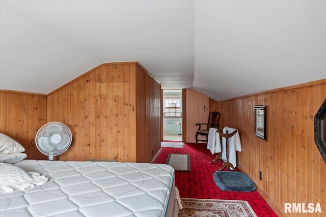 bedroom featuring lofted ceiling, carpet flooring, and wooden walls