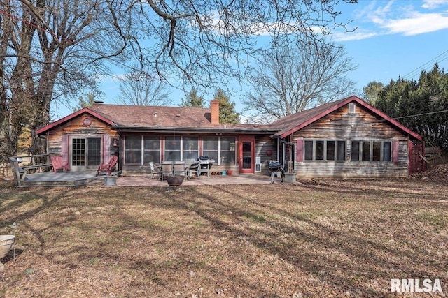 rear view of house featuring a sunroom, a patio, and a lawn