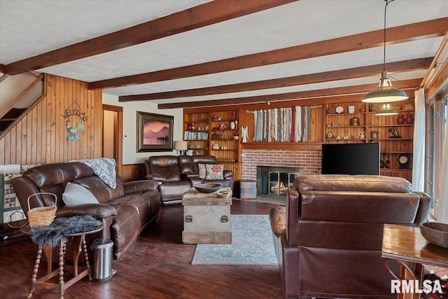 living room featuring dark hardwood / wood-style flooring, a brick fireplace, built in shelves, and wooden walls