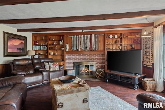 living room featuring beam ceiling, dark hardwood / wood-style floors, a fireplace, built in shelves, and wood walls