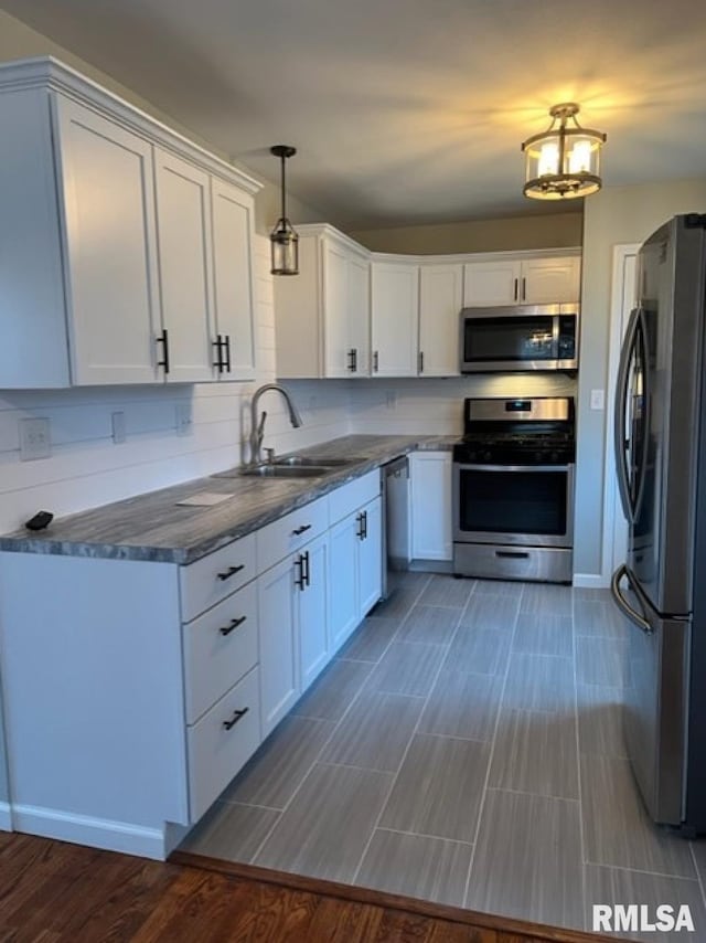 kitchen with sink, decorative light fixtures, appliances with stainless steel finishes, hardwood / wood-style floors, and white cabinets