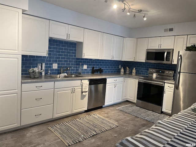 kitchen with white cabinetry, stainless steel appliances, sink, and decorative backsplash