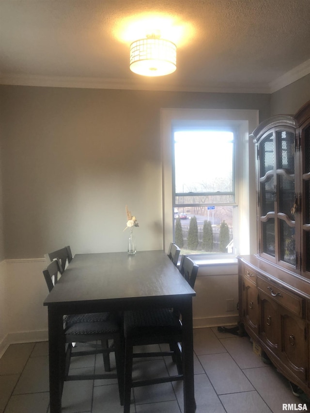 dining area featuring ornamental molding, light tile patterned floors, and a textured ceiling