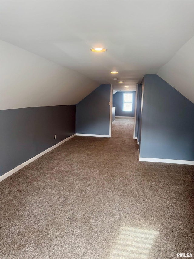 additional living space with lofted ceiling and dark colored carpet