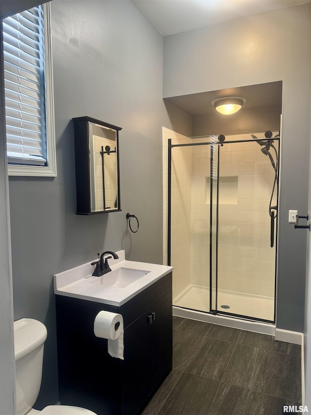 bathroom featuring vanity, a shower with shower door, and toilet