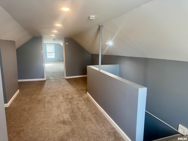 corridor with carpet floors and vaulted ceiling