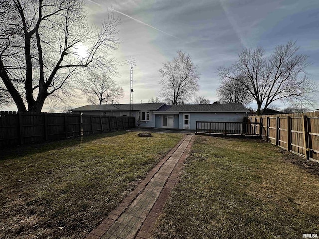 rear view of house with a wooden deck, a yard, and a fire pit