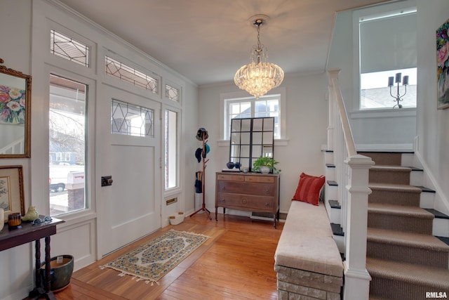 foyer with an inviting chandelier, ornamental molding, and light wood-type flooring