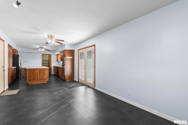 kitchen featuring french doors, a center island, a textured ceiling, stainless steel refrigerator, and ceiling fan