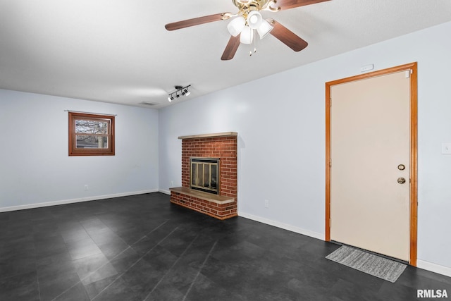 unfurnished living room featuring ceiling fan and a brick fireplace