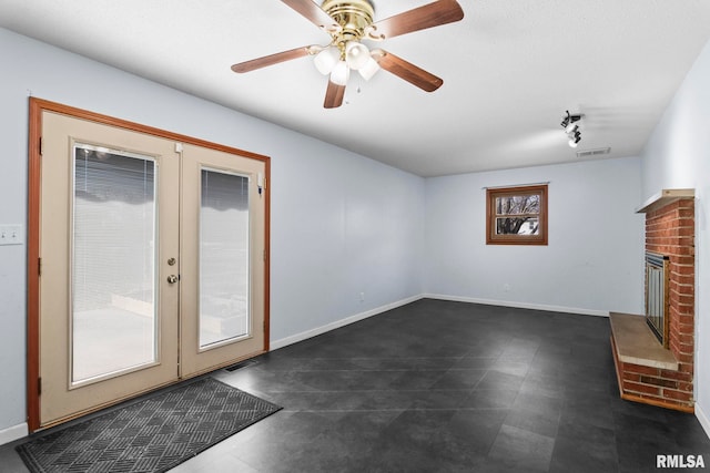 unfurnished living room featuring a wealth of natural light, a fireplace, rail lighting, and french doors