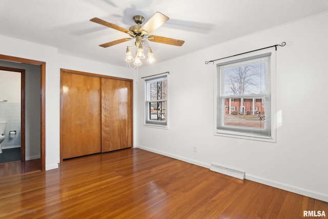 unfurnished bedroom with multiple windows, hardwood / wood-style flooring, a closet, and ceiling fan