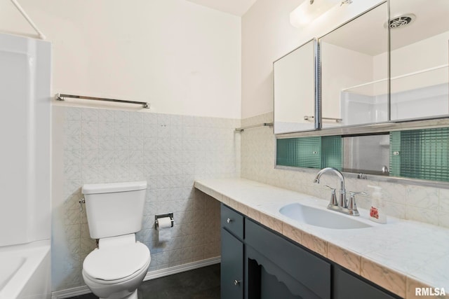 full bathroom with vanity, toilet,  shower combination, and tile walls