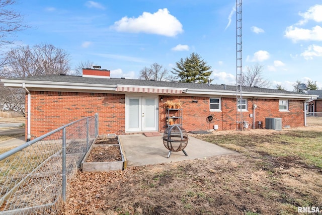 rear view of house featuring a patio area, central AC unit, and a fire pit