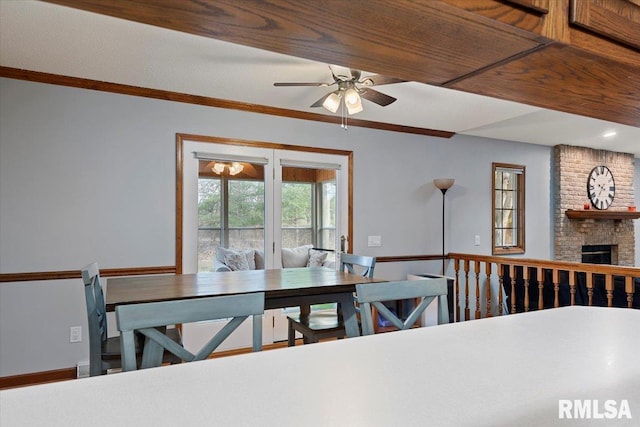 dining room featuring crown molding, ceiling fan, and a brick fireplace