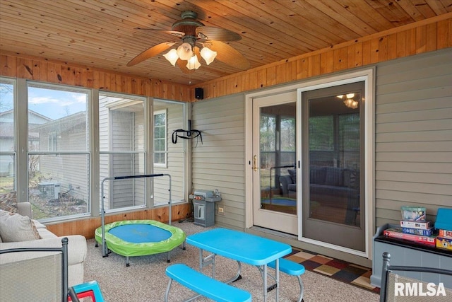 sunroom / solarium with ceiling fan, a healthy amount of sunlight, and wood ceiling