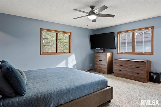 bedroom featuring light carpet, ceiling fan, and a textured ceiling