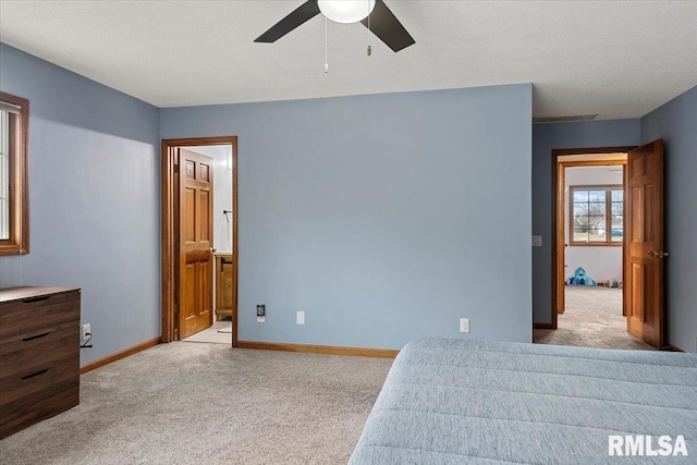 bedroom with ceiling fan, ensuite bath, and light carpet