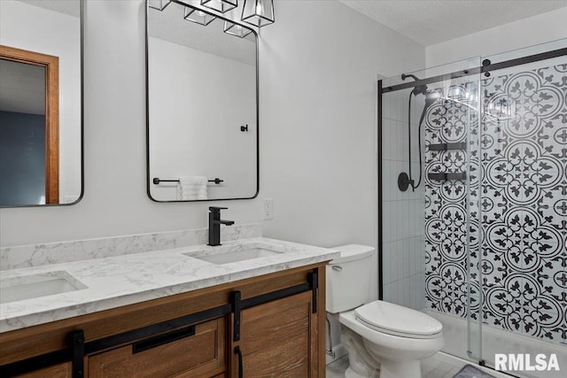 bathroom with a shower with door, vanity, a textured ceiling, and toilet