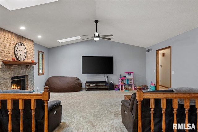 carpeted living room featuring a brick fireplace, lofted ceiling with skylight, and ceiling fan