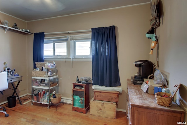 interior space with baseboard heating, ornamental molding, and light wood-type flooring