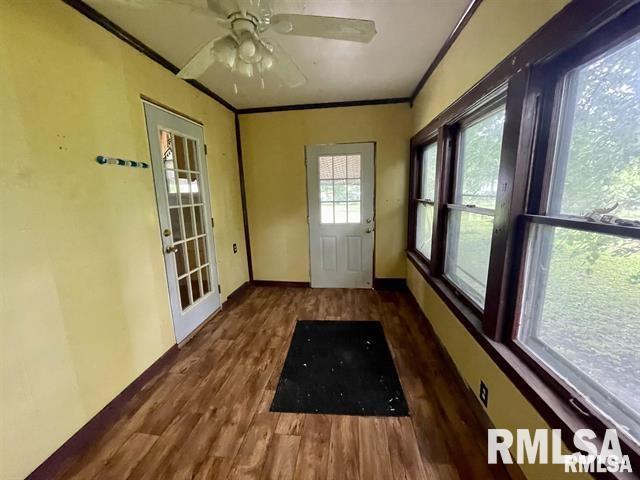 doorway to outside with dark wood-type flooring, ceiling fan, and ornamental molding